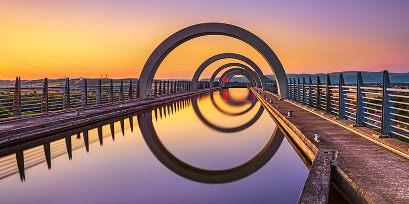 Falkirk Wheel at sunset. Falkirk Wheel is a rotating boat lift in Scotland and connects the Forth and Clyde Canal with the Union Canal. Long exposure.